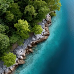 Crystal clear turquoise water gently laps against the rocky shore of a lush tropical beach, showcasing nature's beauty in this aerial view by leeyongjay.