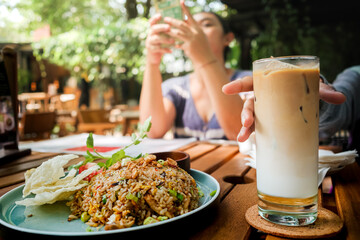 Asian family activity during lunch time at an outdoor restaurant with fried rice and iced coffee milk served on the table
