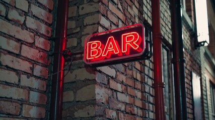 A neon bar sign illuminates a brick wall at night. The warm glow of the red light contrasts with the cool tones of the surrounding environment, creating a vibrant nightlife atmosphere.