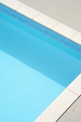Blue swimming pool with tiled edges seen from above on a sunny day.