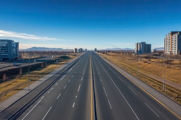 Fototapeta premium Deserted highway stretching to distant city skyline under clear blue sky