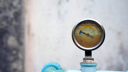 Pressure gauge on machinery with a weathered look against a blurred background.