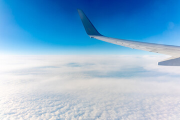 View from the airplane window at a beautiful cloudy sky and the airplane wing