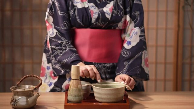 A person dressed in traditional Japanese kimono serving a tray with matcha tea set