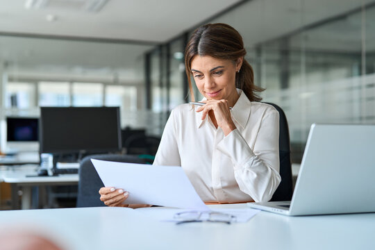 Busy mature business woman bank account manager working in office checking legal document account invoice in office. Businesswoman of middle age executive, attorney lawyer using laptop at work.