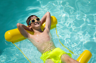 Smiling and relaxed boy enjoying a sunny day on a yellow pool float looking up