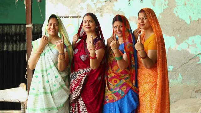 Election in india. Group of rural indian women standing in queue showing finger after casting vote. Voters.