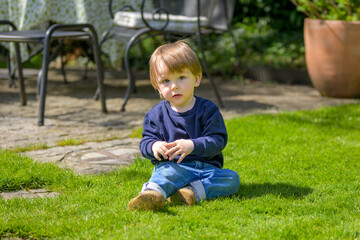 Child Sitting On Garden Lawn