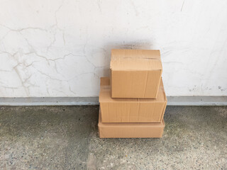 Stacked Cardboard Boxes Against a Cracked White Wall Background