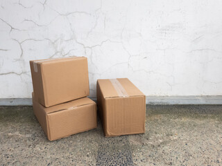 Stacked Cardboard Boxes Against a Cracked White Wall Background