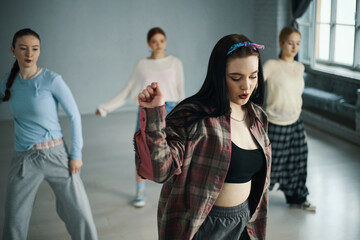 Group of young women engaged in dance practice in a spacious room with natural lighting pouring...