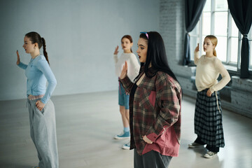 Group of young women practicing dance moves in studio with natural daylight coming through windows,...