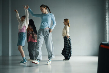 Diverse group of teens engaging in dance practice inside spacious studio. They wear casual,...