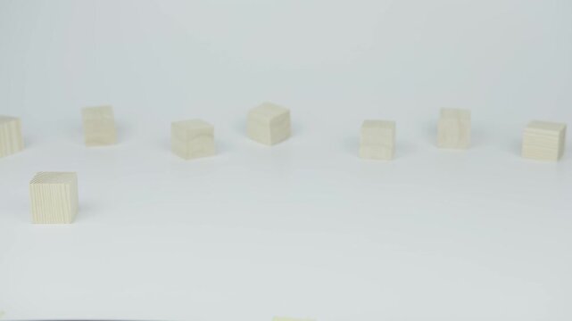 A hand places a wooden block with the number twelve next to another block on a white background, symbolizing connection, sequence, or completion in a minimal and focused setup