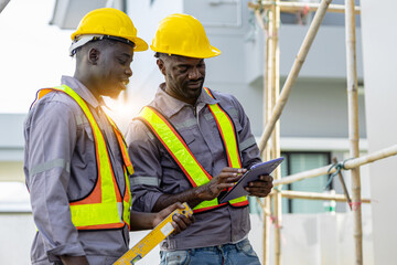 african ethnicity Architect and contractor working on building in construction site. Two Professional Architects Engineer Working on Personal laptop computer at house construction site