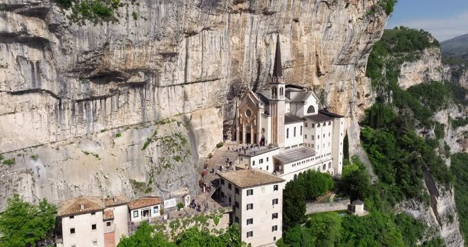 Tourists Visiting The Famous Church Of Madonna della Corona On The Cliff In Italy. - aerial pullback shot