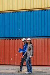 Fototapeta premium Industrial engineer standing at shipping container yard inspecting cargo delivering loading as plan. Woman manager and diverse ethnic worker checking import export container at logistic terminal dock.