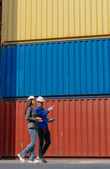 Industrial engineer standing at shipping container yard inspecting cargo delivering loading as plan. Woman manager and diverse ethnic worker checking import export container at logistic terminal dock.