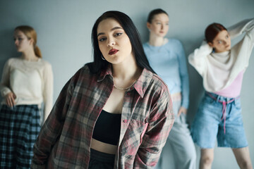 Portrait of four diverse young women posing in casual attire with relaxed expressions. The soft lighting and neutral background emphasize the stylish yet comfortable clothes the women are wearing