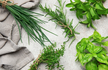 Freshly picked herbs of thyme, basil, mint, rosemary and chives lying on gray table