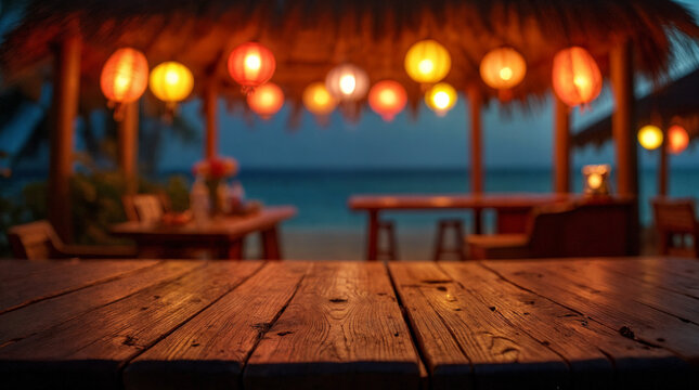 Outdoor photo of an empty wood countertop in the front, with a slightly blurred background of a tiki bar at night with colorful paper lanterns in a beach with an empty wooden sign