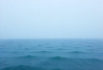 Calm Ocean Surface with Gentle Waves Under a Misty Sky in Shades of Blue and Gray