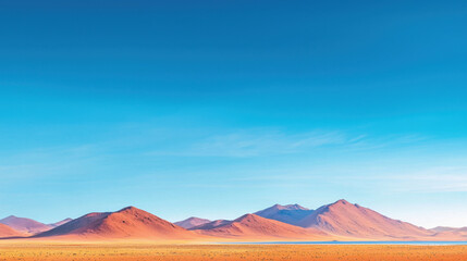 Naklejka premium Stunning desert landscape featuring vibrant orange mountains under clear blue sky, creating serene and dramatic atmosphere