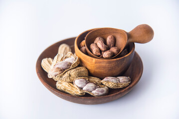 Tiger Peanuts in  wooden bowls a collection of whole peanuts in their shells and a few without shells, healthy snacking concept with peanuts rich in protein and fats.