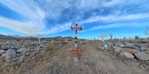Red metal cross at cemetery with stripped sky background