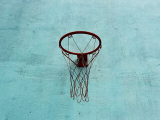 A weathered basketball hoop stands out against a textured blue wall, capturing the essence of urban courts and still moments in sports culture.