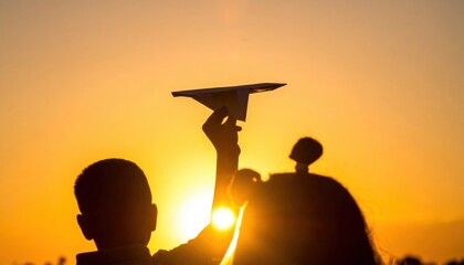 Fototapeta premium Child launches paper airplane at sunset outdoor activity warm atmosphere captured silhouette inspiring moments