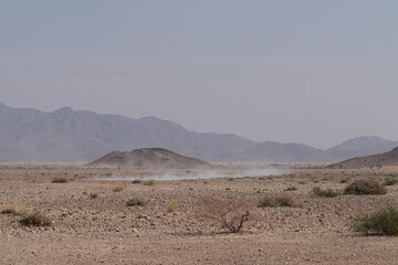 ein Auto hinterlässt aufwirbelnden Staub bei der Durchfahrt durch die Wüste