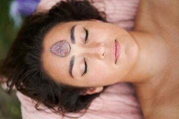 Woman relaxing with crystal stone on forehead during holistic therapy session