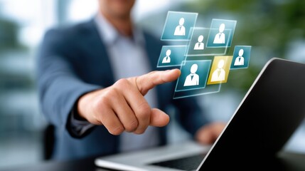 Fototapeta premium A businessman interacts with digital person icons on a laptop screen in modern office.