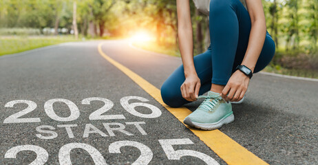 New year 2026 concept, beginning of success. Text 2026 written on asphalt road and women runner preparing for the new year. Concept of challenge or career path and change.