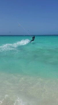 Vertical format man kitesurfer jump over turquoise waters of Caribbean Sea, Los Roques Venezuela.