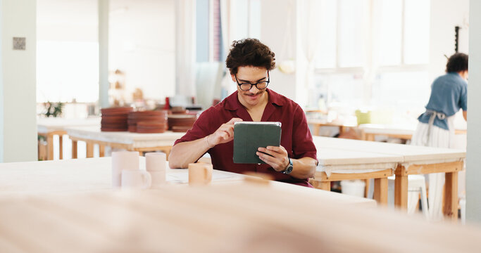 Man, tablet and happy at pottery workshop with update for web store with sculpture, tea cup and typing at studio. Person, digital touchscreen and manager with app for ceramic product with inventory