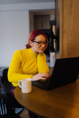 Focused freelancer working remotely from home office using laptop