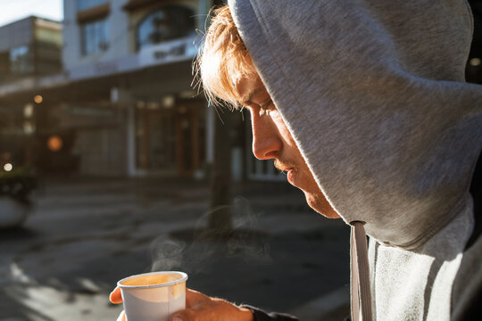Man in hoodie sipping coffee on cool morning in Manly