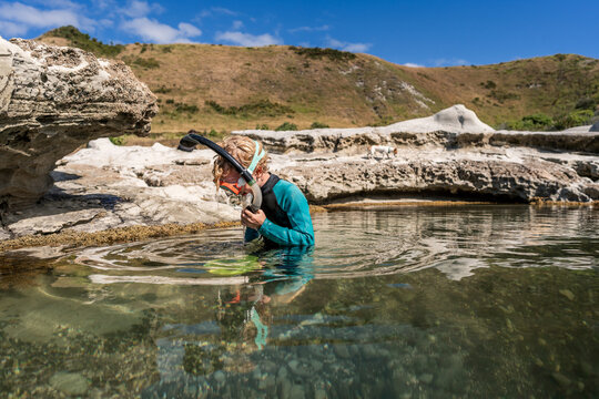 Child with snorkel and mask in tide pool in New Zealand