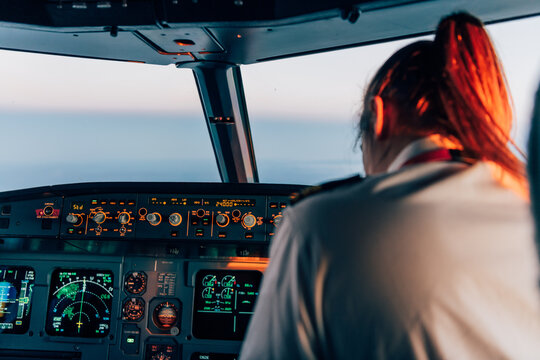 Female pilot in cockpit seen from behind during sunset flight