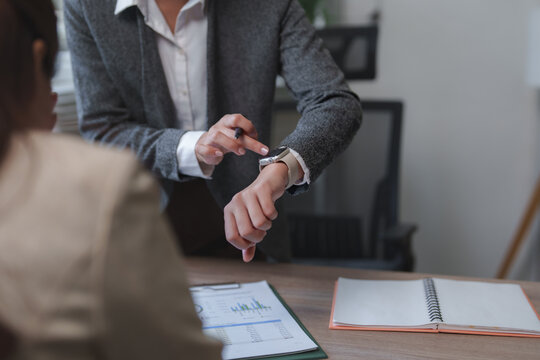 Businesswoman checking time on smartwatch during office meeting