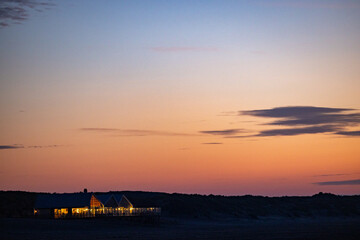 A beautifully serene view of a charming cottage illuminated by twilight, set against a stunning...