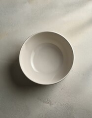 Minimalist empty white bowl placed on a neutral surface, perfect for culinary presentations.