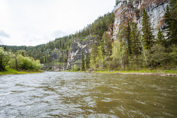 A serene and picturesque river landscape that is beautifully surrounded by majestic cliffs and lush, vibrant forests, providing a perfect setting for exploration and peaceful outdoor adventures