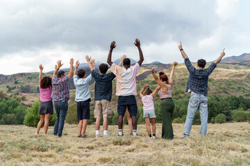 Obraz premium Group of diverse friends raising hands facing nature, celebrating unity and freedom