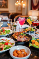 Gourmet Dinner Table with Grilled Lamb, Salads, and Drinks