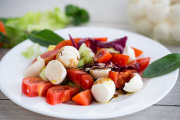 Appetizer with mozzarella, tomatoes and green leaves