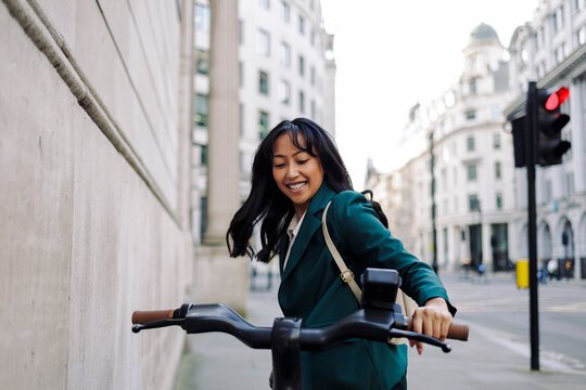 Businesswoman commuting on an electric scooter in London city street