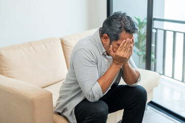 Fototapeta premium Asian mature old man sitting headache tired on sofa at home. Portrait of serious depression sadness senior asian man. Mature People Depressed problem in life